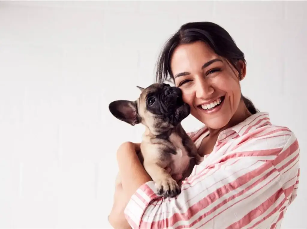 Smiling woman hugging her French Bulldog